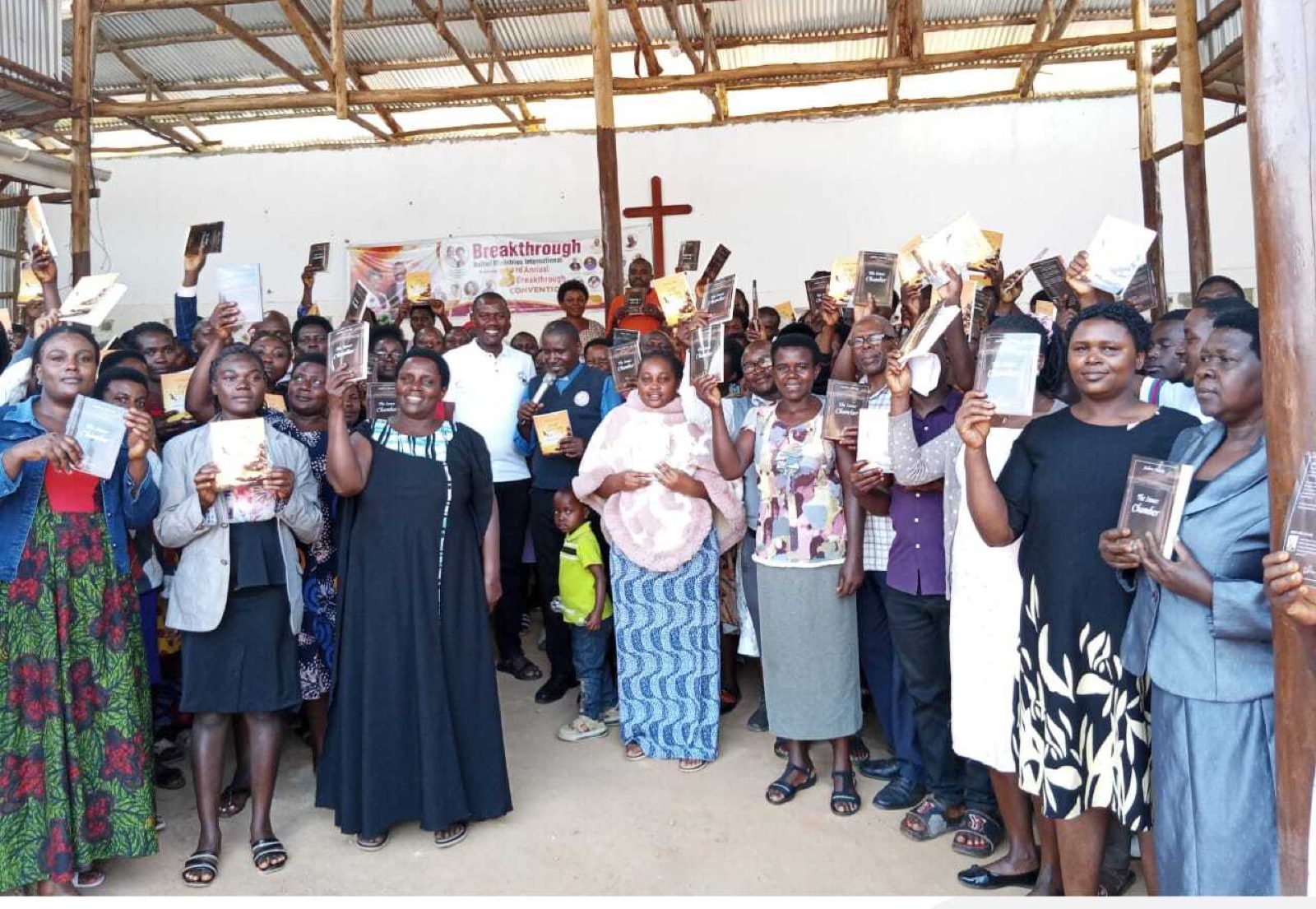 Des croyants tiennent en l’air des livres Ochorus qu’ils viennent de recevoir lors d’un rassemblement d’église en Ouganda
